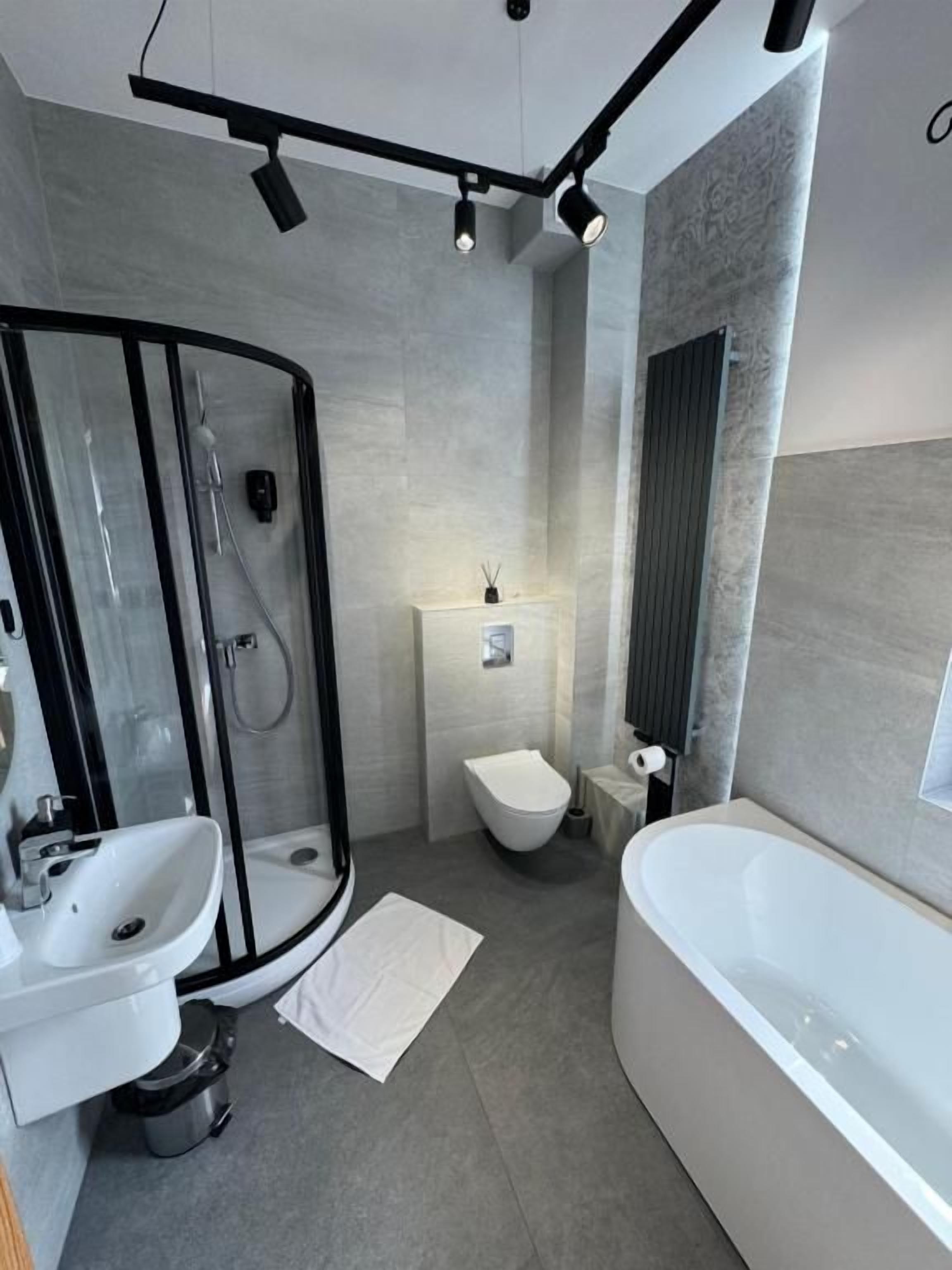 A modern bathroom with a glass shower enclosure, a freestanding bathtub, a toilet, and a sink.
