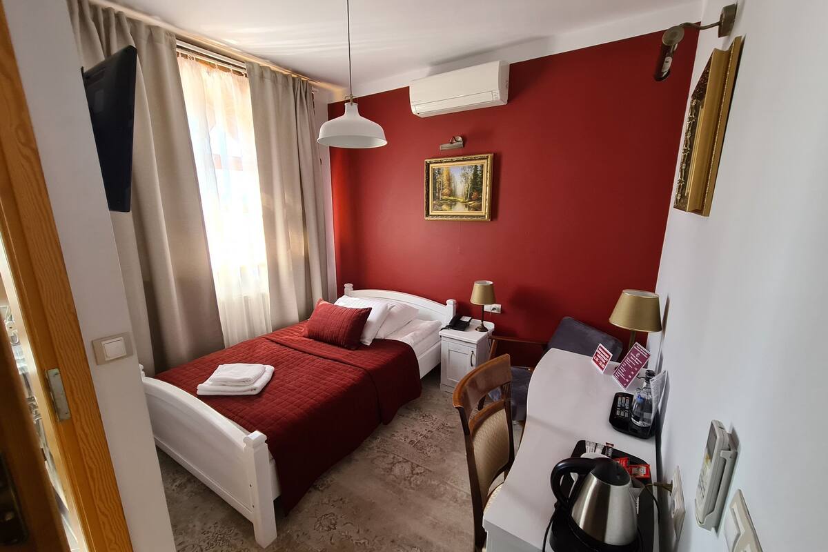 Une chambre d’hôtel équipée d’un lit, d’une table de chevet, d’une lampe et d’une bouilloire.
