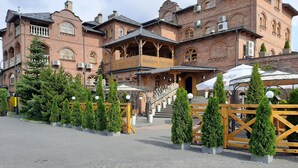 A historic building with a wooden balcony, brick walls, and a paved courtyard with potted trees. - Hotel Staropolski (Tomaszow Lubelski)