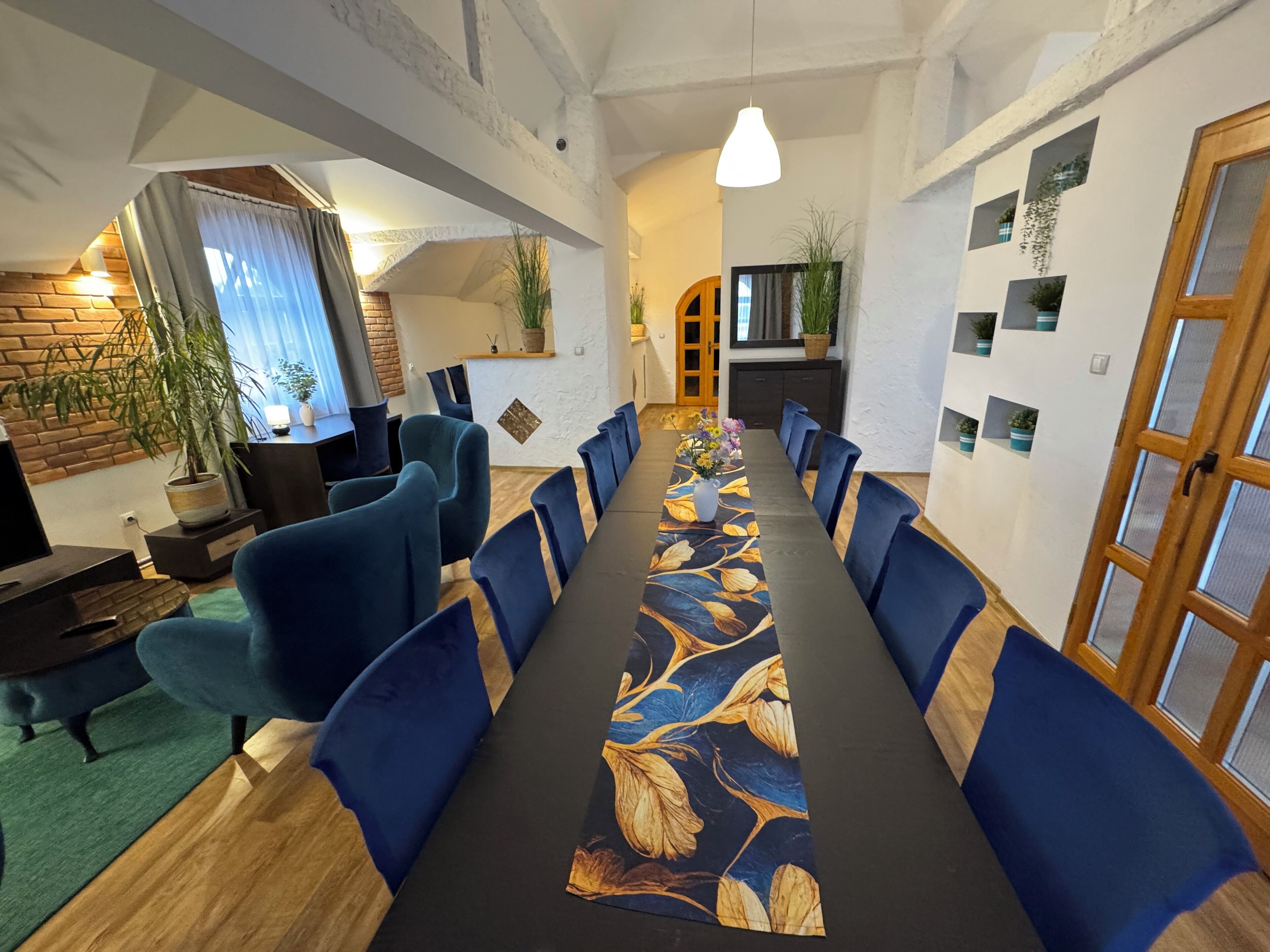 Un salón de conferencias con una larga mesa, sillas azules y un mantel con motivos florales.