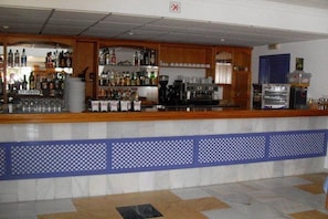 A bar area with shelves of bottles, glasses, and a coffee machine. - Mojacar Playa (Mojacar)