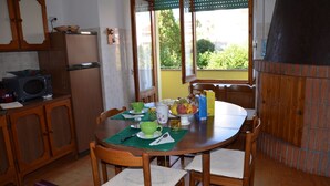 A dining area with a wooden table, chairs, and a view of greenery outside. - B&b Aloysia - Regalati una Vacanza!!!! (Iglesias)