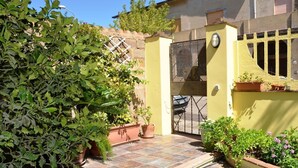 A courtyard with a tiled floor, a yellow wall, and a gate. - B&b Aloysia - Regalati una Vacanza!!!! (Iglesias)