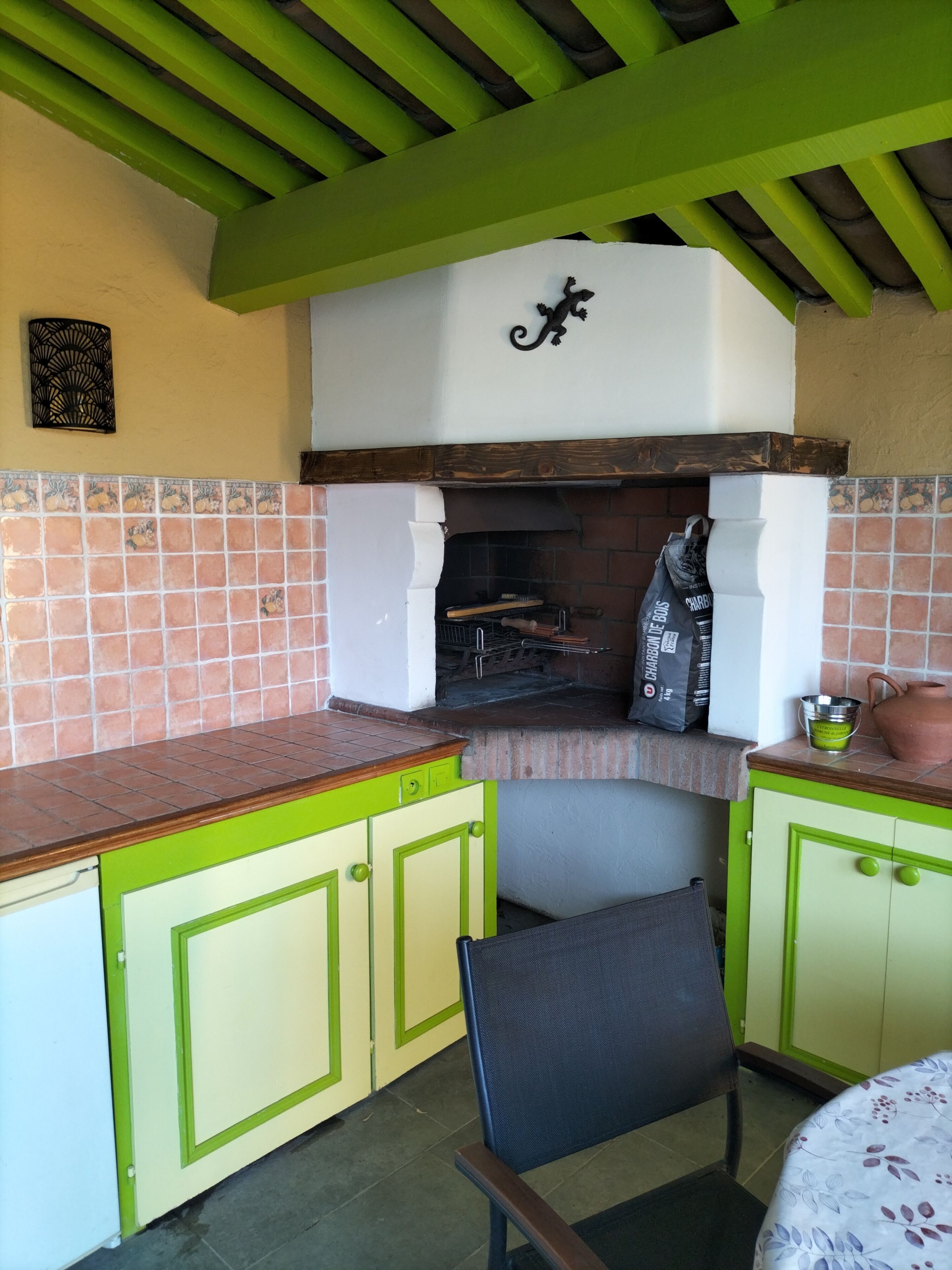 Una cocina con parrilla integrada, armarios verdes y salpicadero de azulejos.