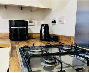 A kitchen with a gas stove, a coffee maker, and a microwave.