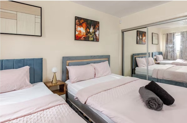 A hotel room with two beds, a large mirror, and artwork on the walls.