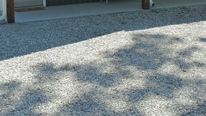Un bâtiment à l’extérieur sombre, avec une porte blanche et un porche doté d’un banc.
