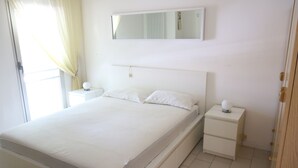 A bedroom with a bed, a bedside table, a nightstand, a mirror, and a door. - Sea Fano holiday apartment (Fano)