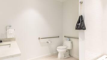 Une salle de bain moderne équipée de toilettes, de barres d’appui, d’un lavabo et d’un porte-serviettes.