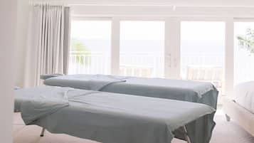 Two single beds with light blue bedding, a balcony with greenery, and a bright, airy atmosphere.