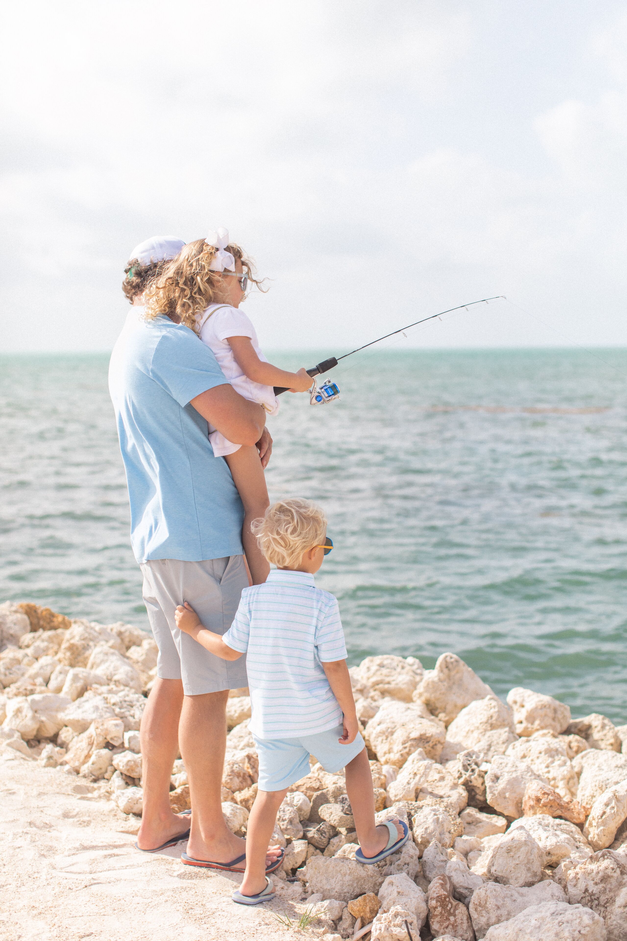 A family of three fishing by the sea.