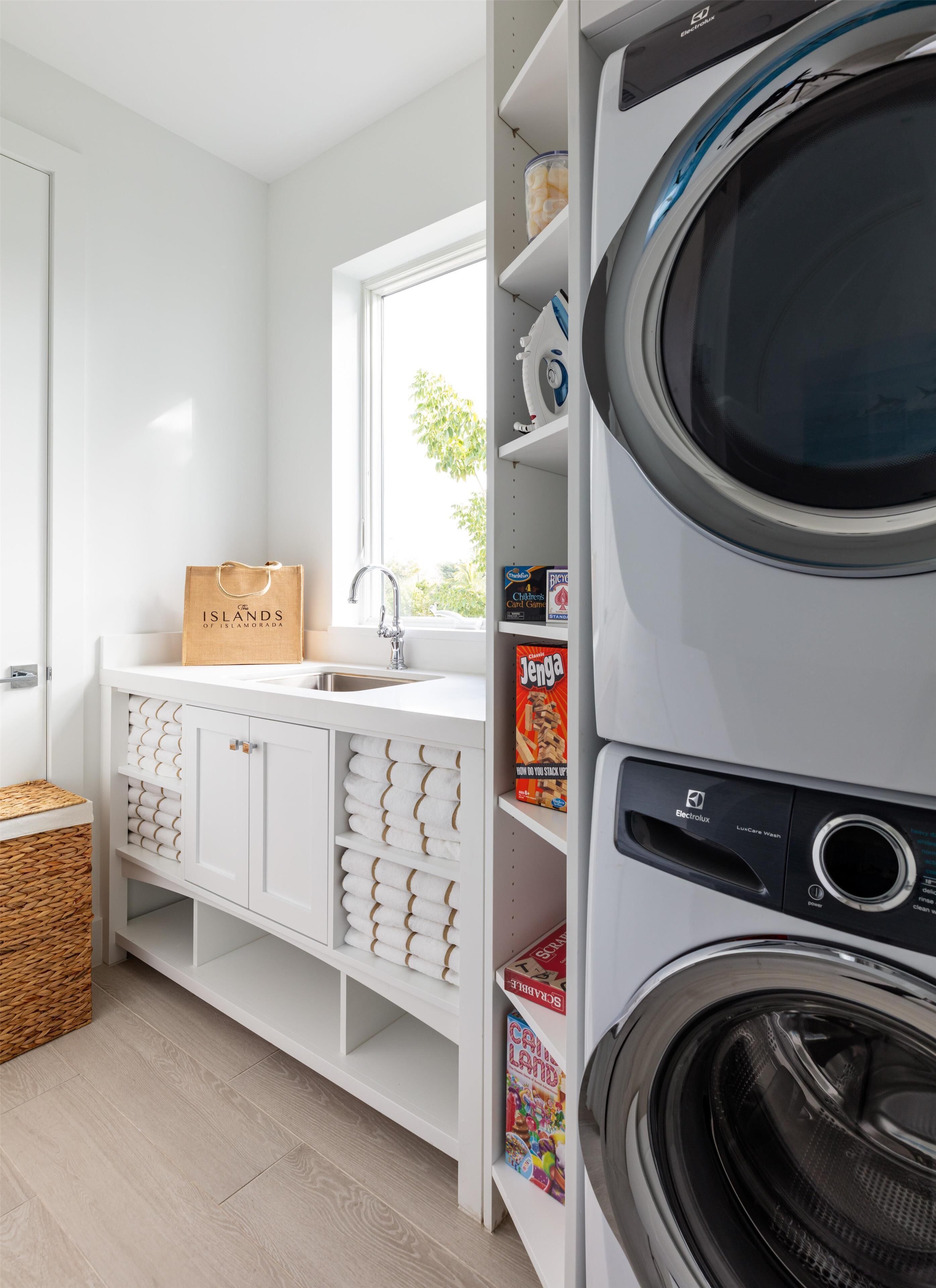 Un cuarto de lavado con lavadora, un lavabo y un armario de almacenamiento con toallas.