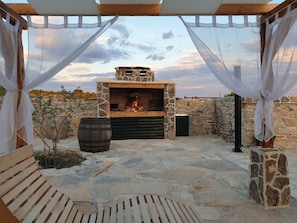 Relax by the stone fireplace in this serene outdoor space, complete with a wooden bench and stone wall.