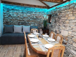 Enjoy meals in a warm, inviting dining area with a rustic stone wall backdrop and a comfortable sofa.