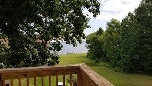 A wooden deck overlooking a grassy area with a body of water in the background. - Rappahannock River Unplugged (Jamaica)