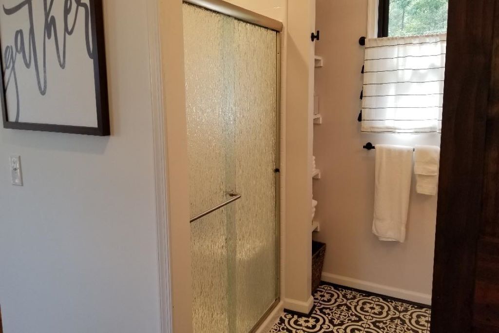 Une salle de bain avec une douche, un porte-serviettes et un panneau encadré accroché au mur.