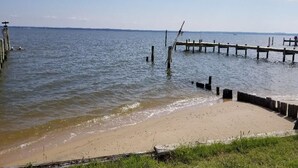 A beach with a wooden pier extending into calm waters. - Rappahannock River Unplugged (Jamaica)