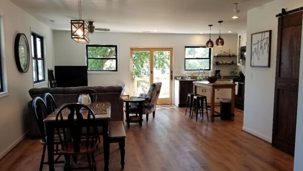A spacious living area with a dining table, chairs, a sofa, and a television. - Rappahannock River Unplugged (Jamaica)