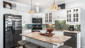 A modern kitchen with white cabinetry, a stainless steel refrigerator, a built-in oven, and a coffee maker.