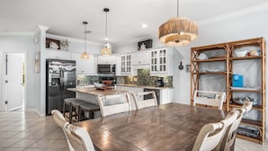 A modern kitchen with white cabinets, stainless steel appliances, and a wooden dining table.