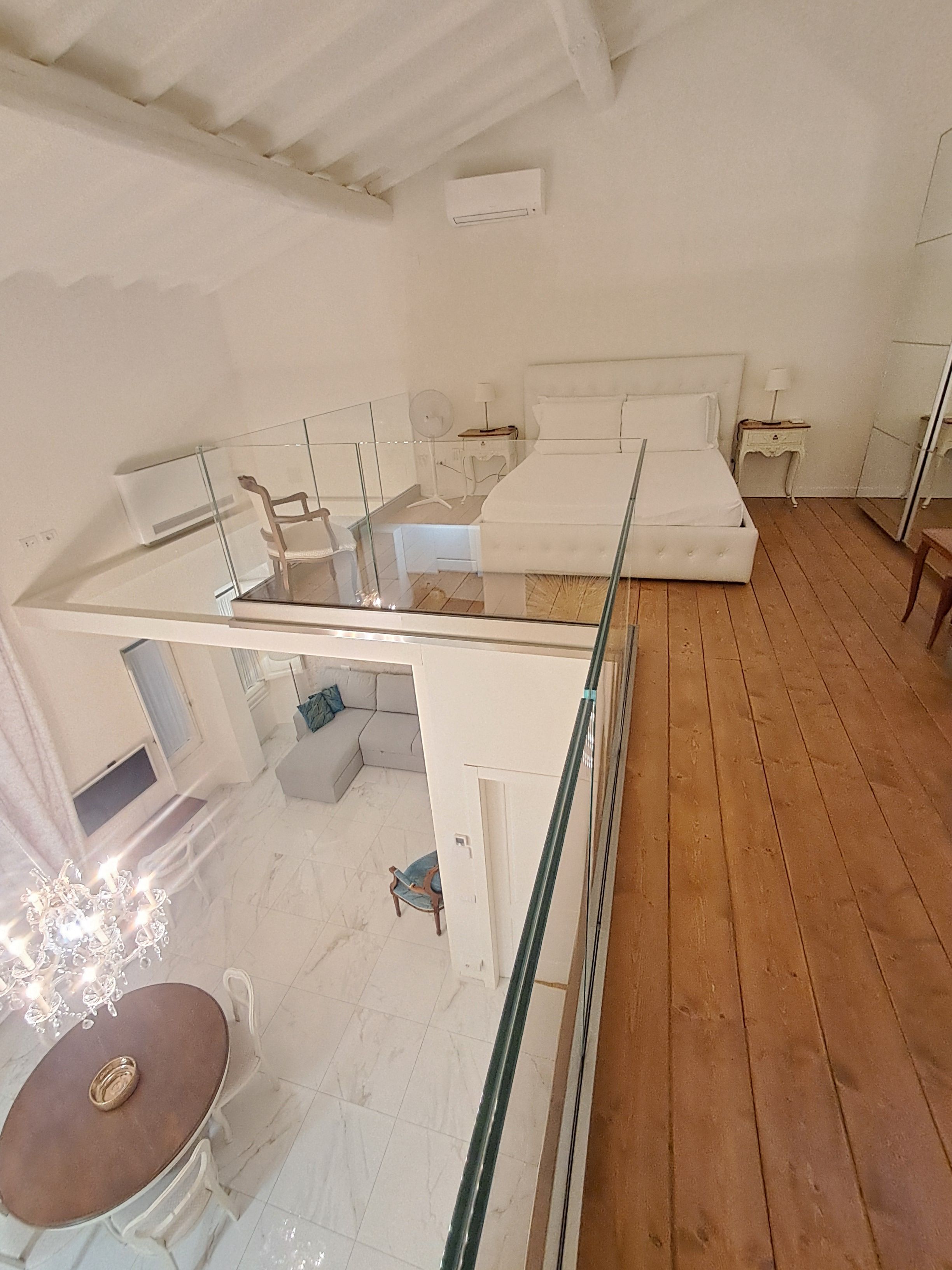 A bedroom with a glass balcony, a bed, a bedside table, and a nightstand.