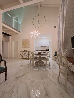 A spacious dining area with a chandelier, a kitchen in the background, and a large mirror on the wall. - New apartment near the Duomo with Wi-Fi and an elevator (Firenze)
