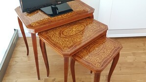 Ein Flachbildfernseher auf einem Holztisch mit aufwendigen Mustern, stehend auf einem Holzboden.