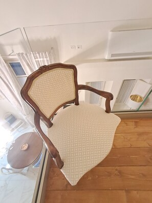 A chair with a wooden frame and a patterned seat, positioned near a window with curtains. - New apartment near the Duomo with Wi-Fi and an elevator (Firenze)