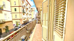 A narrow balcony with a tiled floor, metal railing, and a view of adjacent buildings. - B&B Rianna House (Naples)