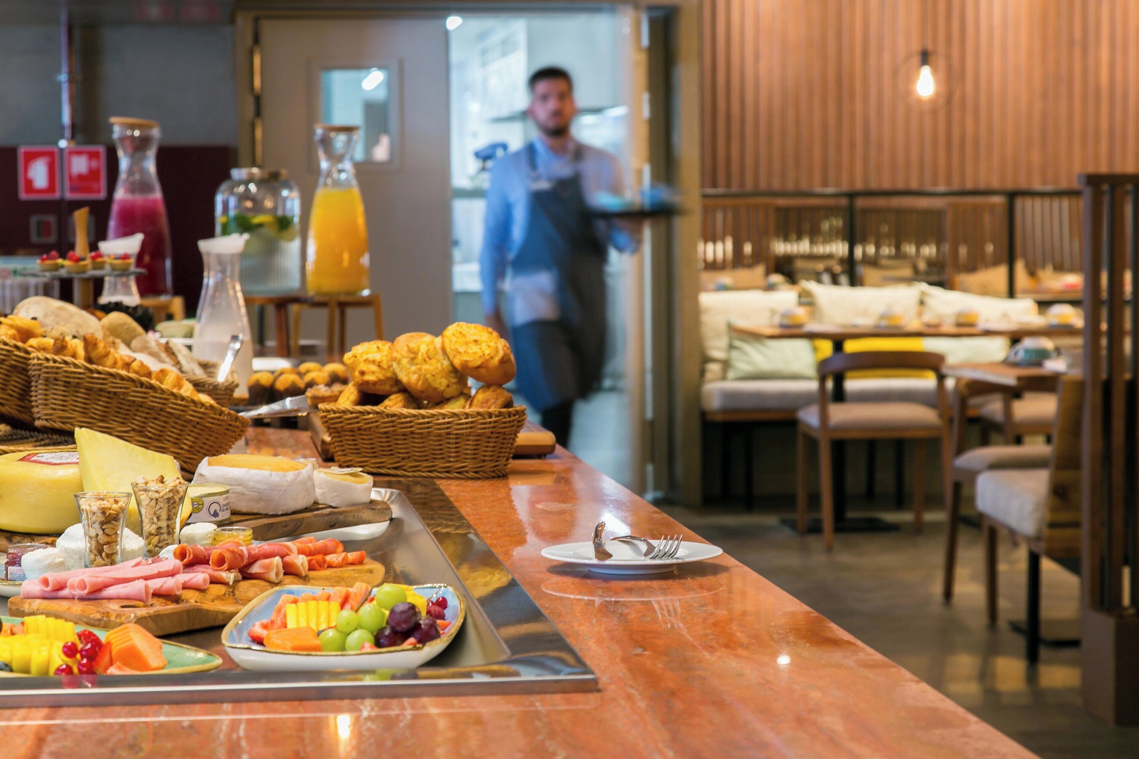 A breakfast buffet with various cheeses, meats, and fruits.