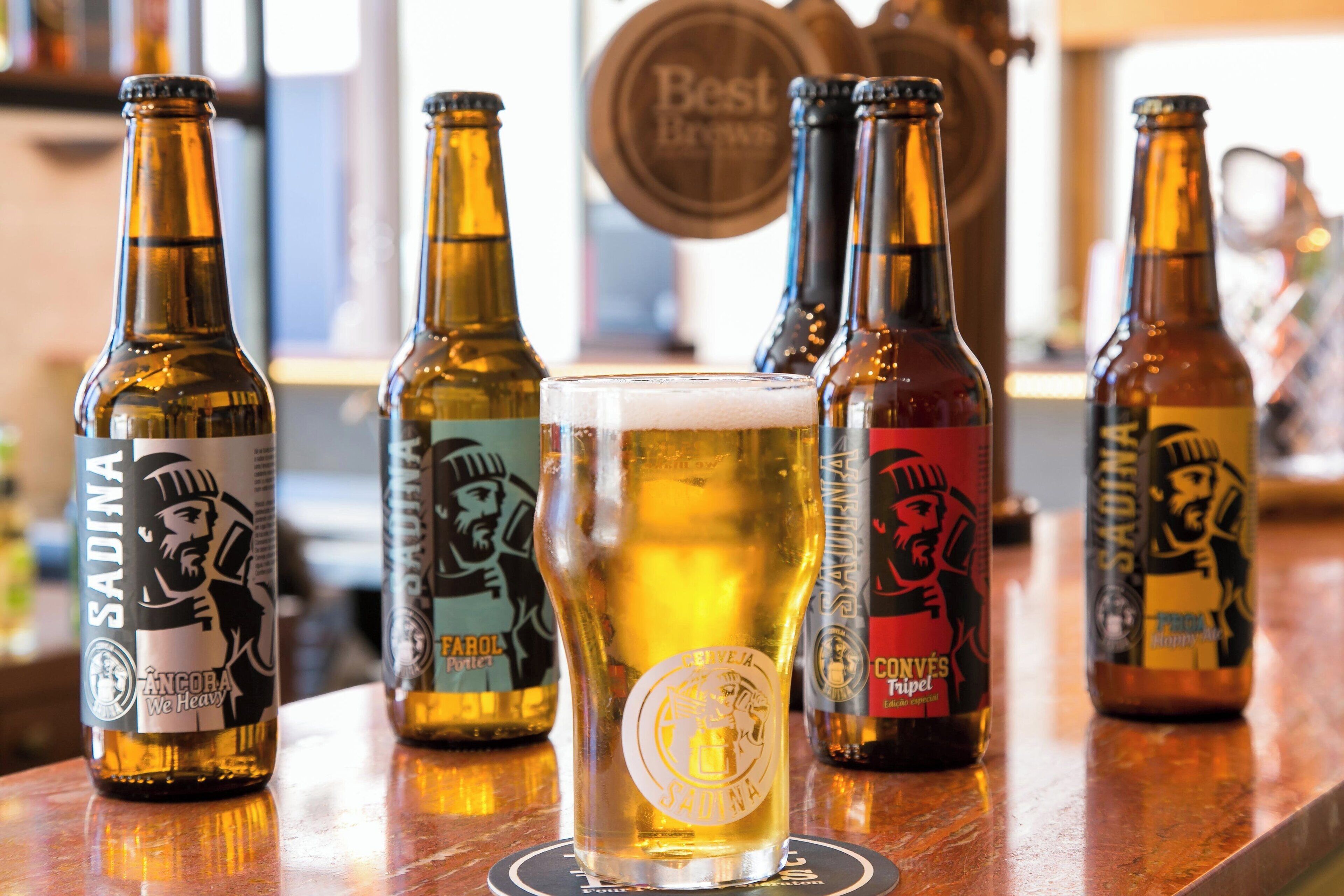 A bar with several bottles of beer and a glass of beer on a coaster.