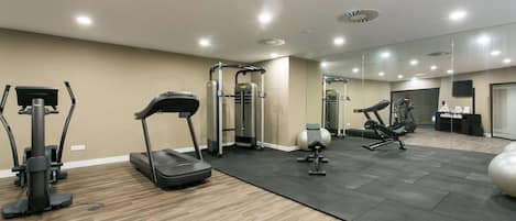 A gym with treadmills, a weight machine, and exercise balls.
