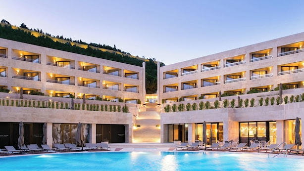 Un hotel moderno con piscina central, varios balcones y una escalera que conduce a los pisos superiores.