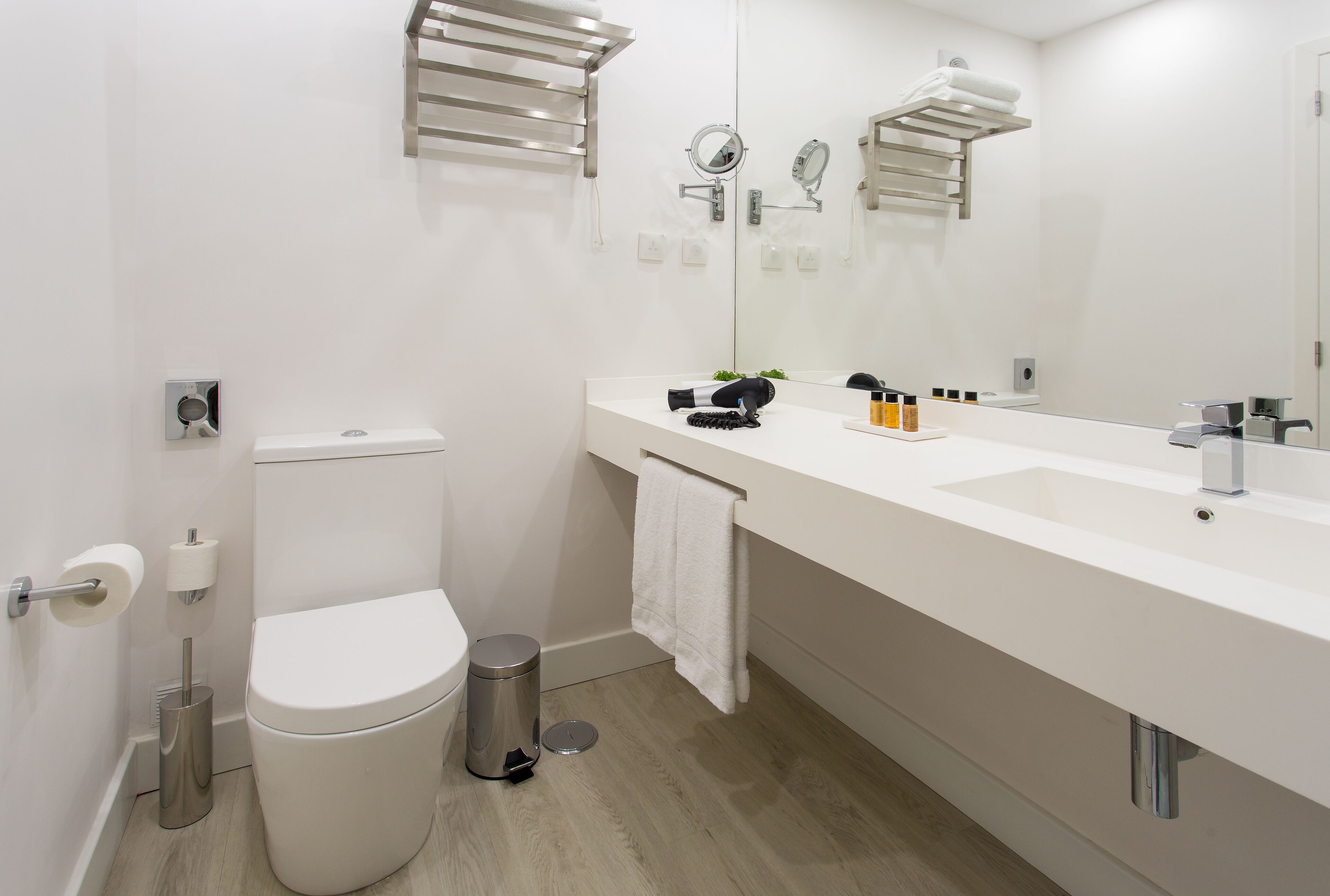 A modern bathroom with a toilet, bidet, sink, and large mirror.