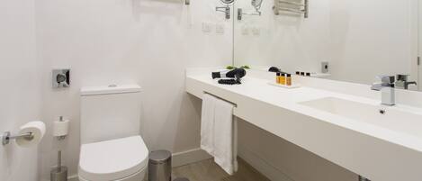 A modern bathroom with a toilet, bidet, sink, and large mirror.