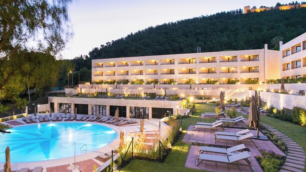 Un hôtel doté d’une piscine, de plusieurs balcons et offrant une vue sur une colline.
