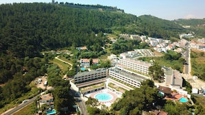 Un hotel con un patio central, rodeado de edificios y una ladera boscosa.