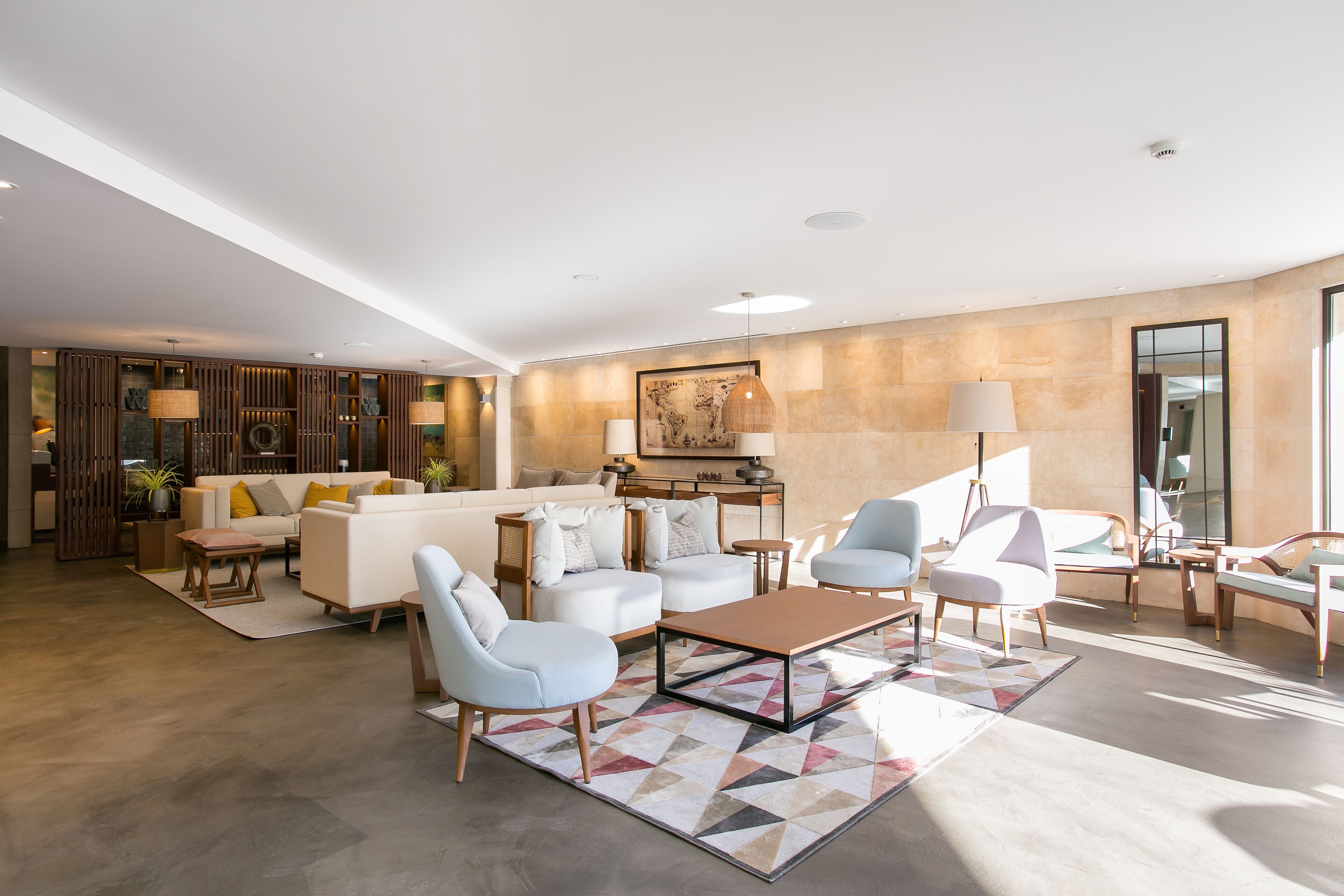A spacious living room with a modern sofa set, a coffee table, and a dining area with a lamp.