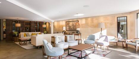 A spacious living room with a modern sofa set, a coffee table, and a dining area with a lamp.