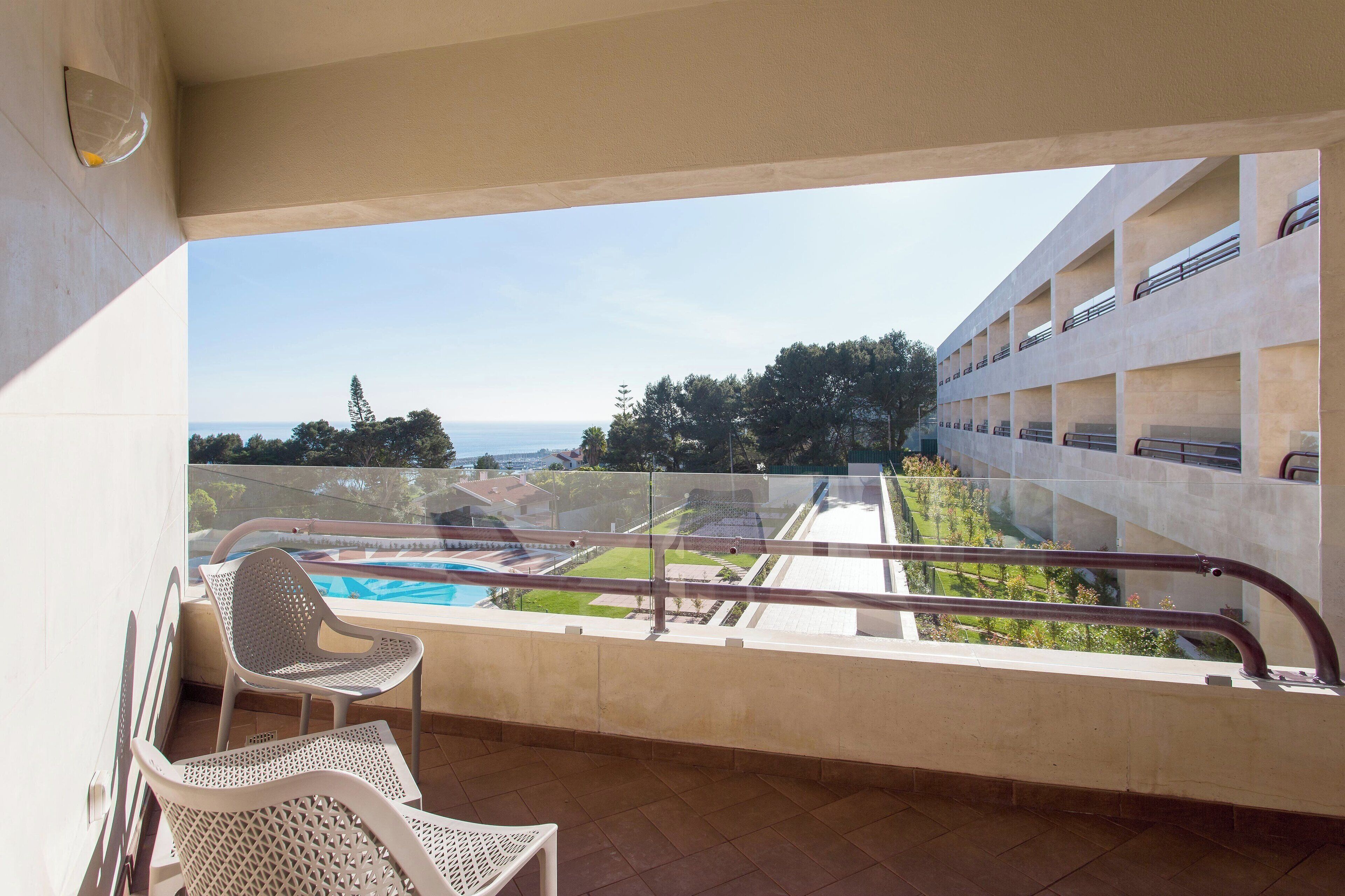 A balcony with a view of a swimming pool and a building with multiple balconies.