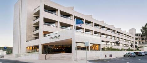 A multi-story hotel with a modern design, featuring balconies and a prominent entrance.