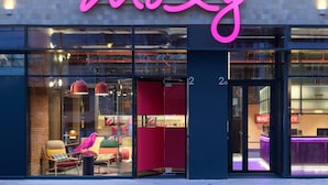 A modern building with a neon sign reading "moxy" and a glass storefront. - Moxy Lisbon City (Lisbon)