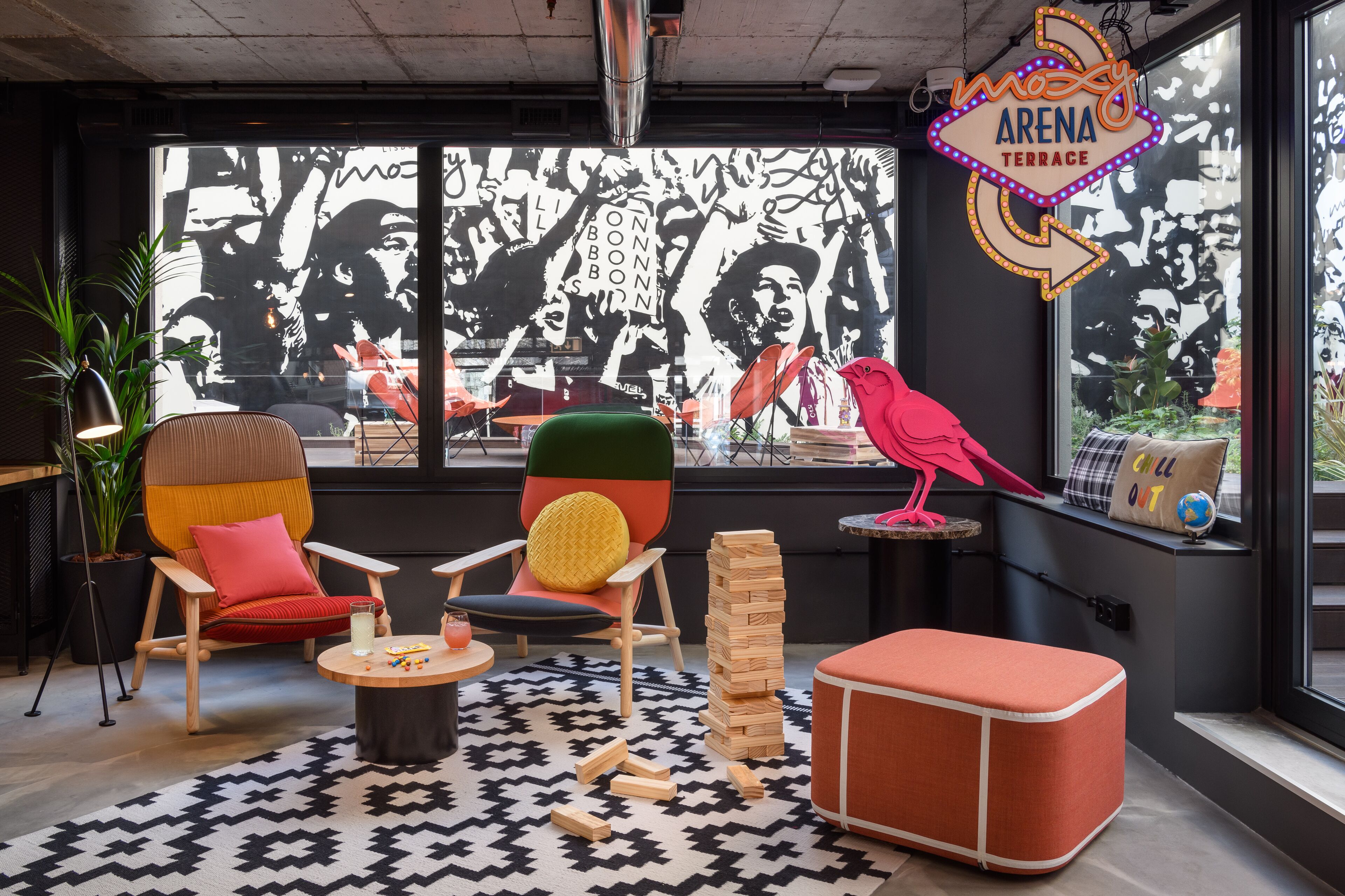 Et moderne loungeområde med behagelige siddepladser, et stort vindue med et muralmaleri og en neonskilte.