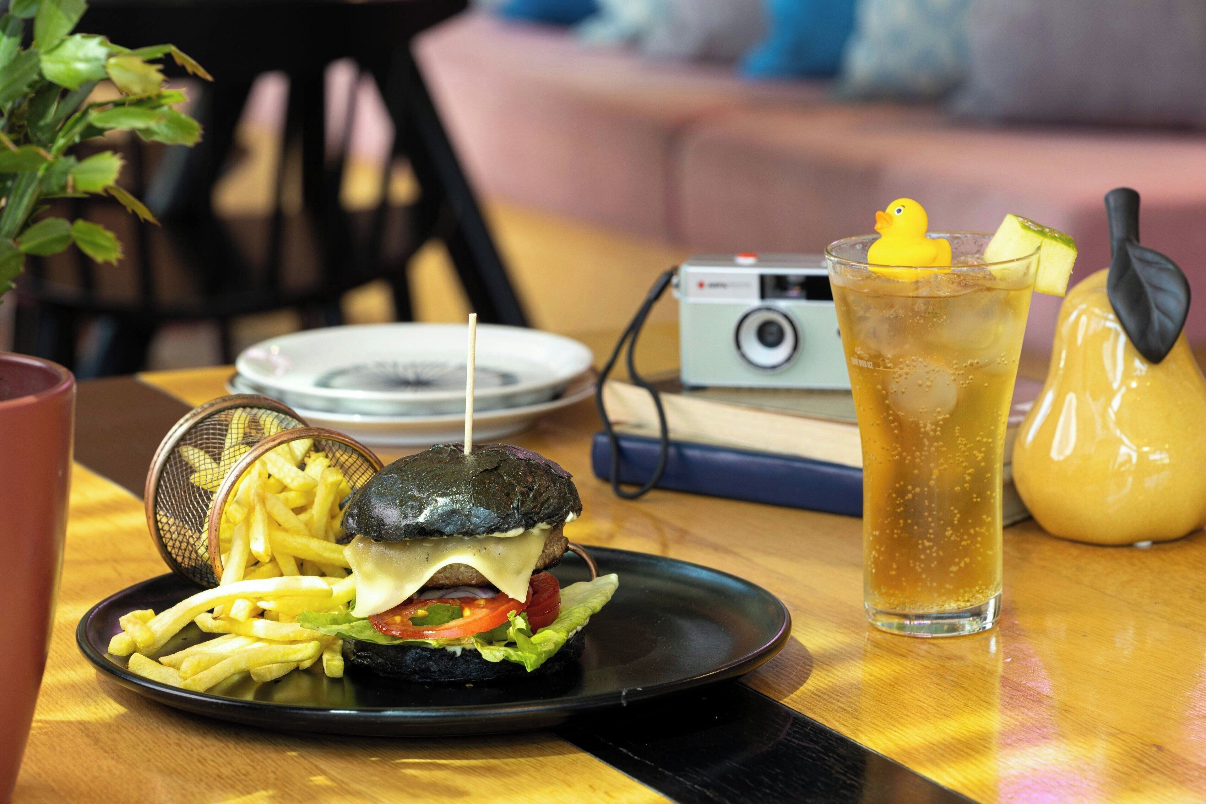 Un repas composé d’un hamburger, de frites et d’une boisson, servi sur une table.