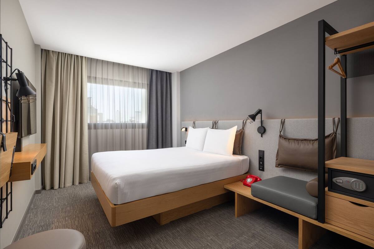 Een moderne hotelkamer met een groot bed, nachtkastjes, een bureau en een stoel.