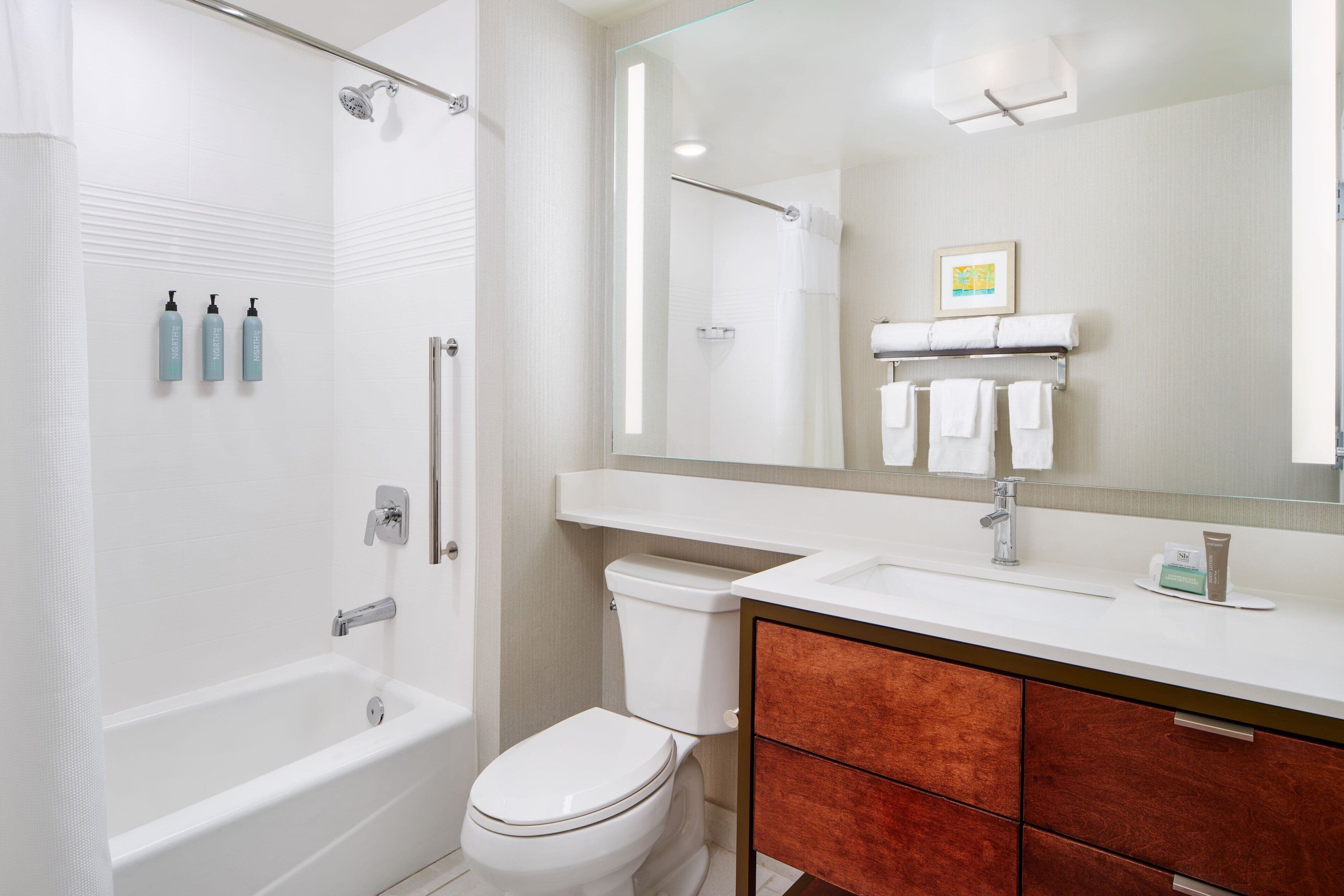 A modern bathroom with a bathtub, toilet, and vanity.