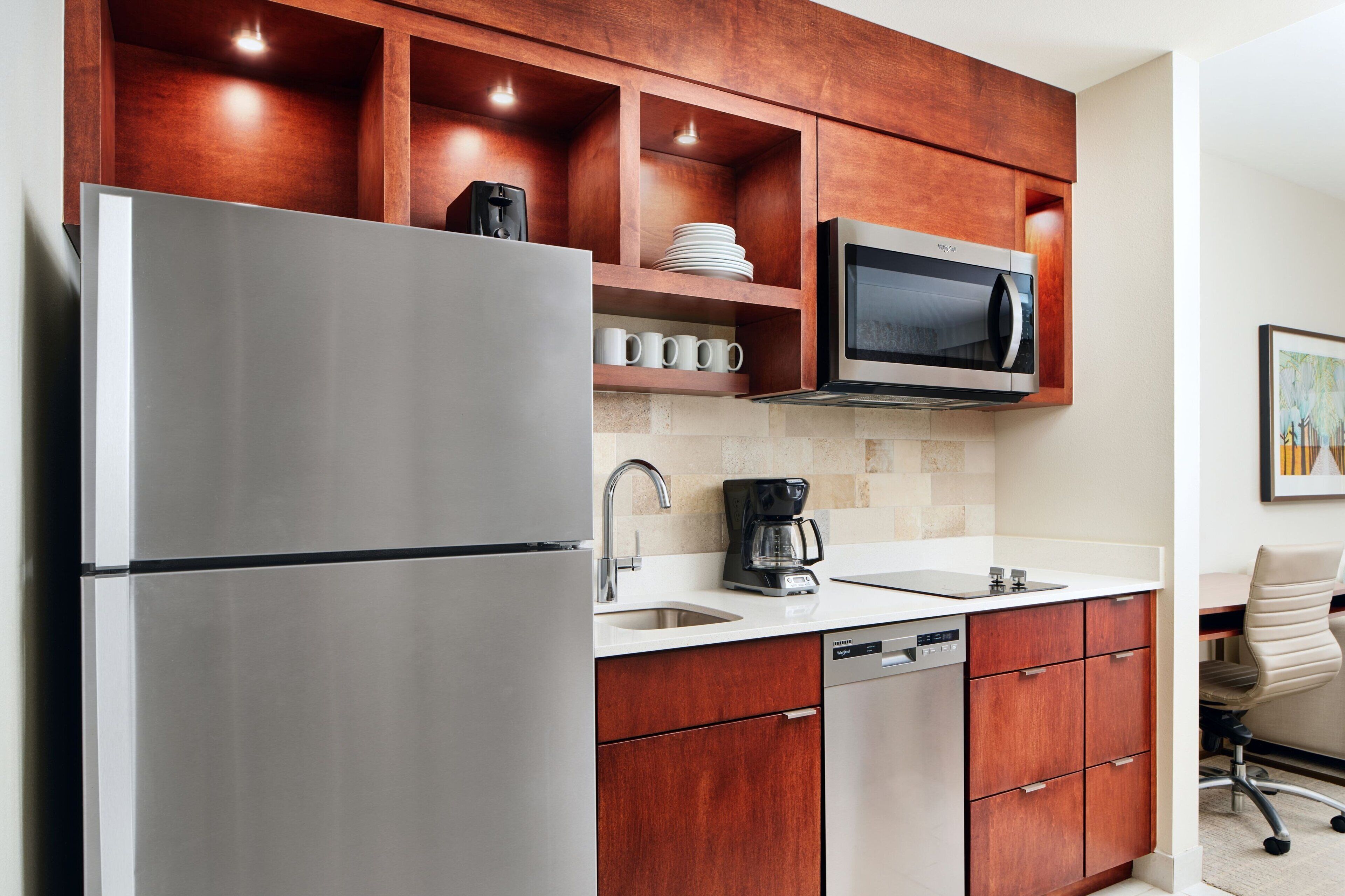 Une cuisine moderne dotée d’appareils électroménagers en acier inoxydable, de meubles en bois et d’un lave-vaisselle.