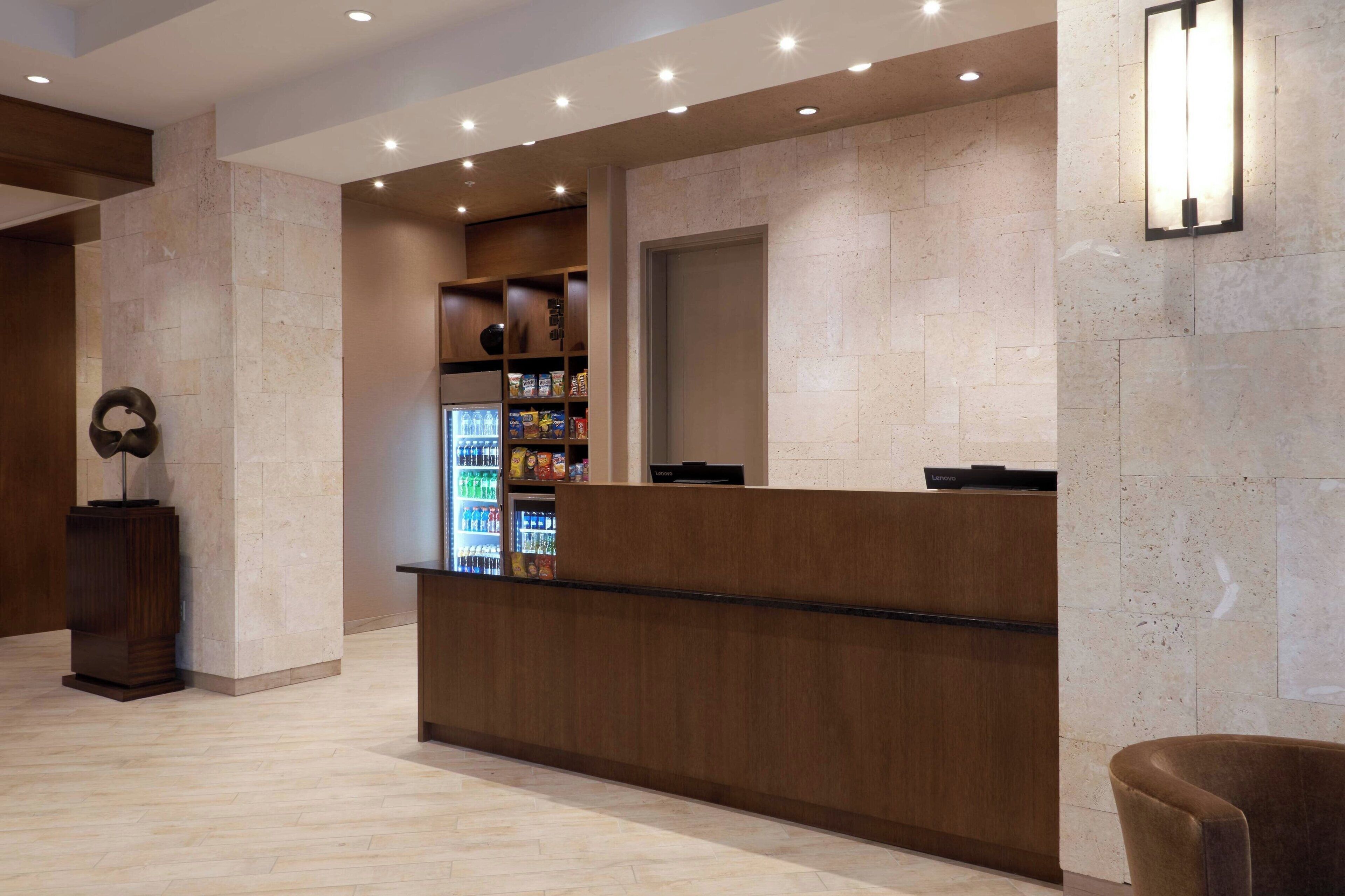 A reception area with a wooden reception desk, a beverage refrigerator, and a wall-mounted light fixture.