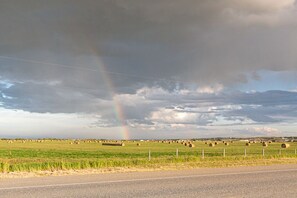 A rural landscape with hay bales and a rainbow. - Log cabin on the James River in Alberta (James River Bridge)