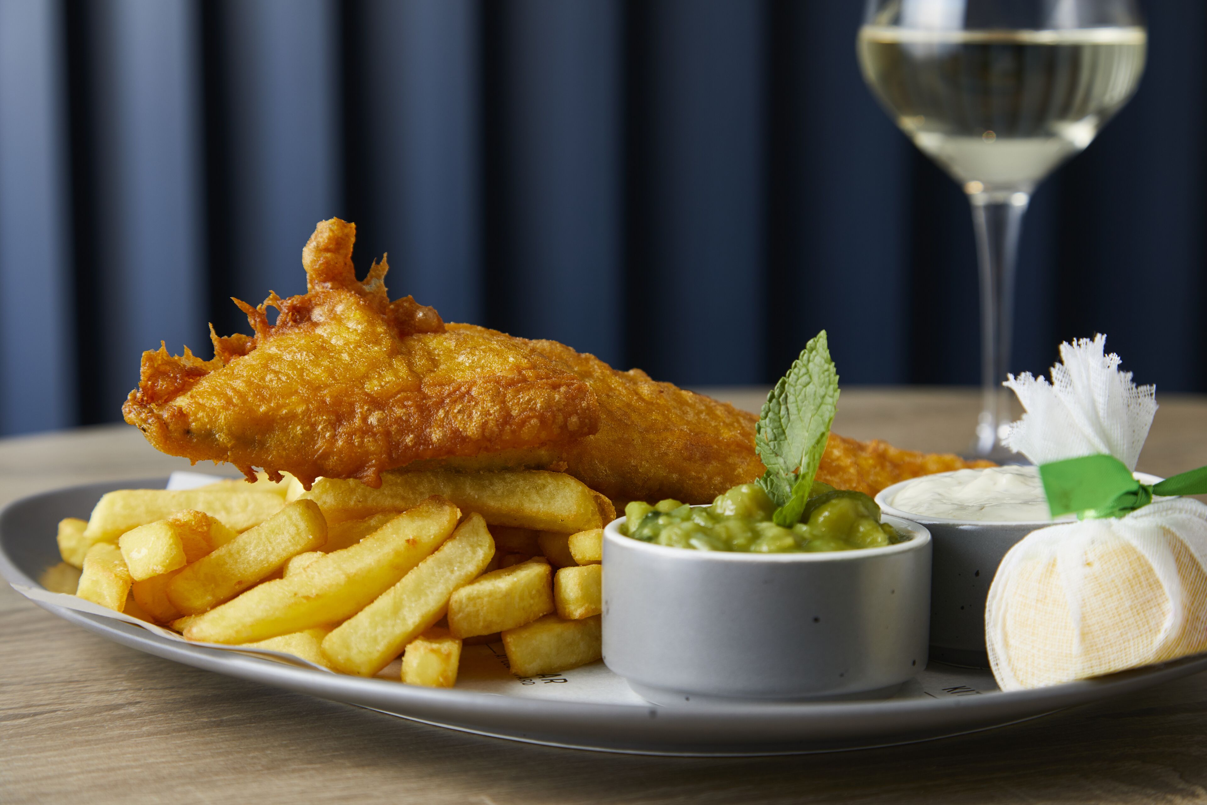 Ein Teller Fish and Chips mit einem Glas Weißwein.